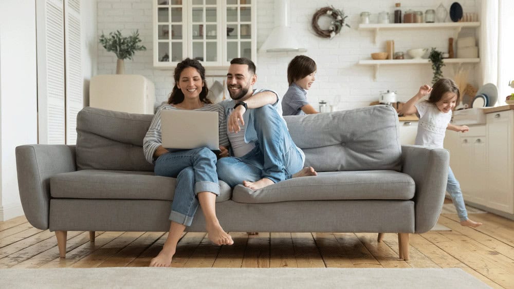 young family sitting in a new build house enjoying their entertainment on a laptop